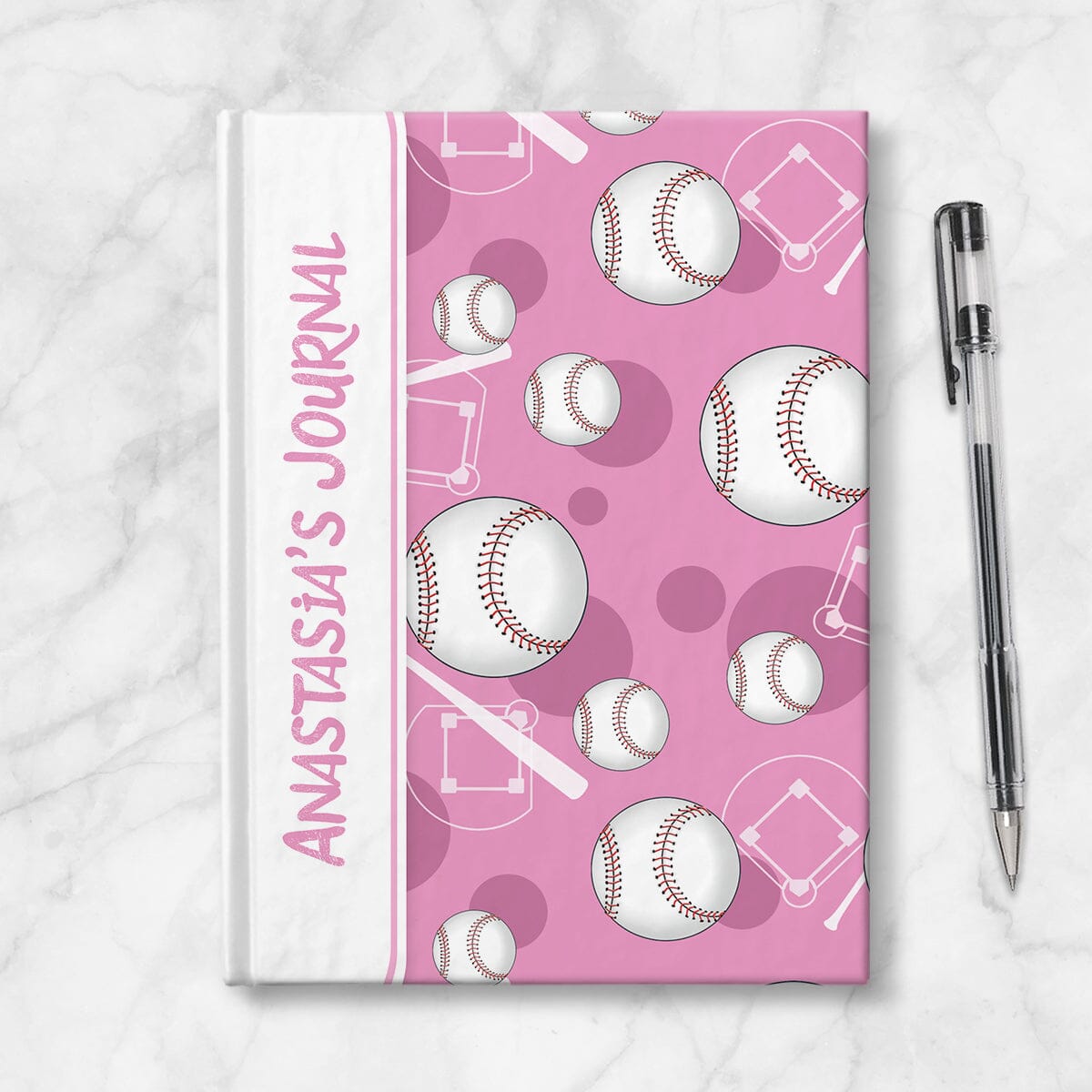 Personalized Pink Baseball Journal at Artistically Invited. Image shows the book on a countertop next to a pen.