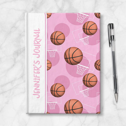 Personalized Pink Basketball Journal at Artistically Invited. Image shows the book on a countertop next to a pen.