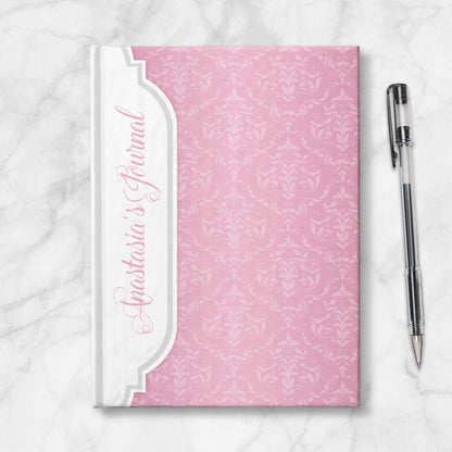 Personalized Pink Damask Journal at Artistically Invited. Image shows the book on a countertop next to a pen.