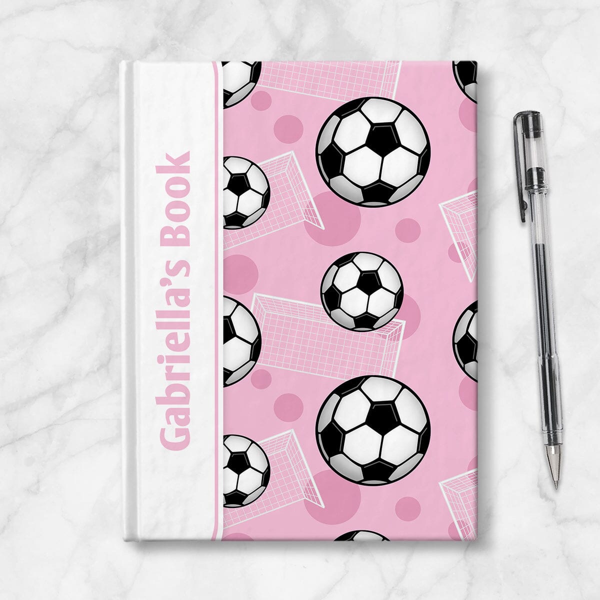 Personalized Pink Soccer Journal at Artistically Invited. Image shows the book on a countertop next to a pen.