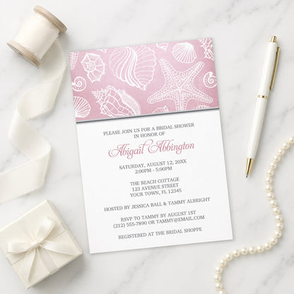Pink Beach Seashell Pattern Bridal Shower Invitation shown on a marble surface with a white gift box, pen, ribbon, and pearls.