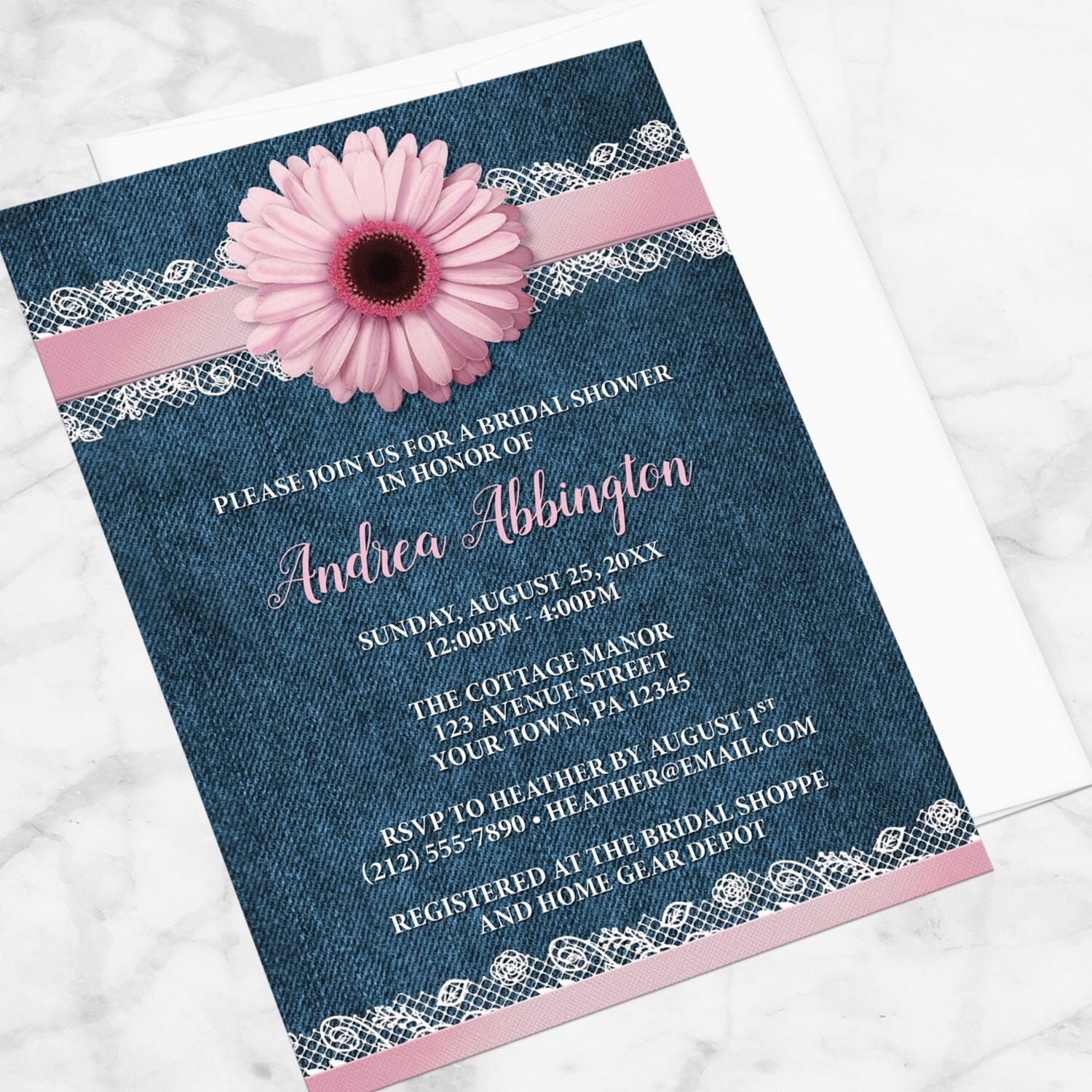 Bridal shower invitation with a pink daisy, denim and lace, displayed at an angle with a white envelope on a marble surface