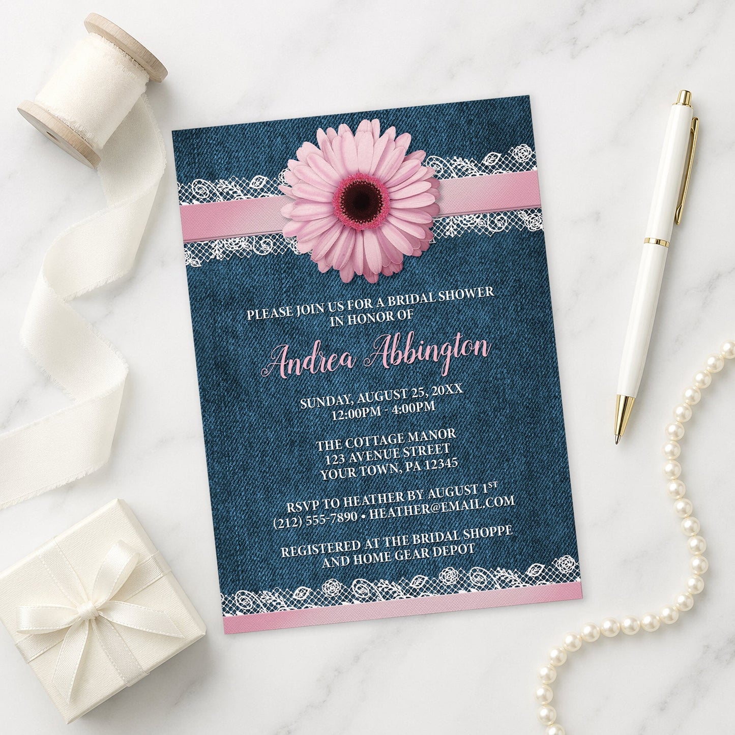 Pink Daisy Lace Rustic Denim Bridal Shower Invitation on a marble surface with a white gift box, ribbon, pen, and pearls.