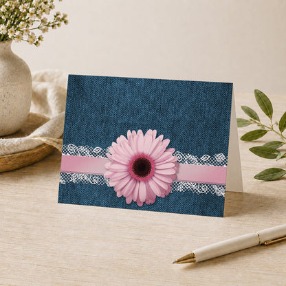 Pink Daisy Lace Rustic Denim Note Card shown on a desk with a vase, plants, and a pen.
