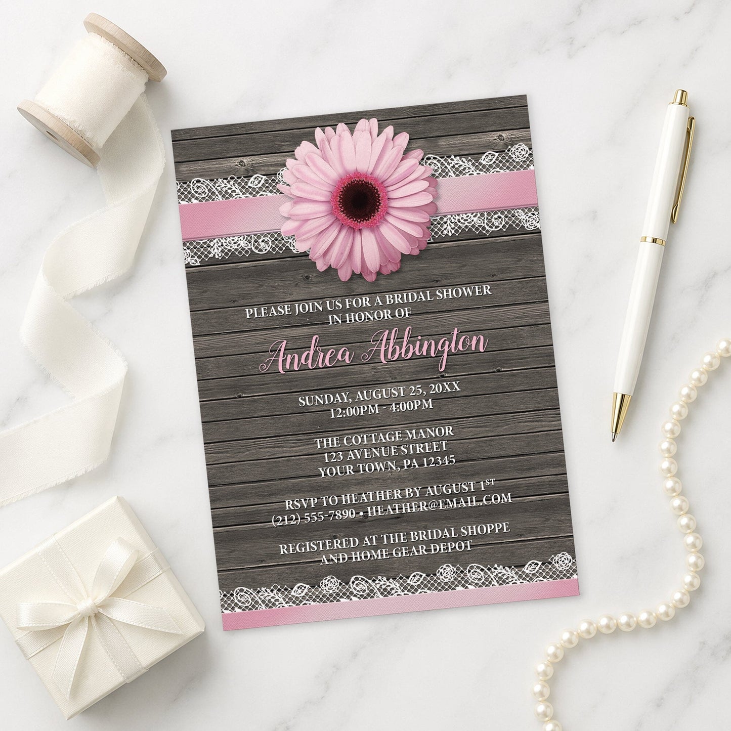 Pink Daisy Lace Rustic Wood Bridal Shower Invitation shown on a marble surface with a white gift box, pen, ribbon, and pearls.
