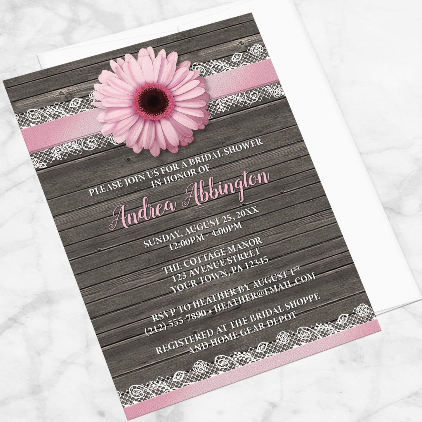 Pink Daisy Lace Rustic Wood Bridal Shower Invitation shown at an angle on a marble surface with a white envelope.