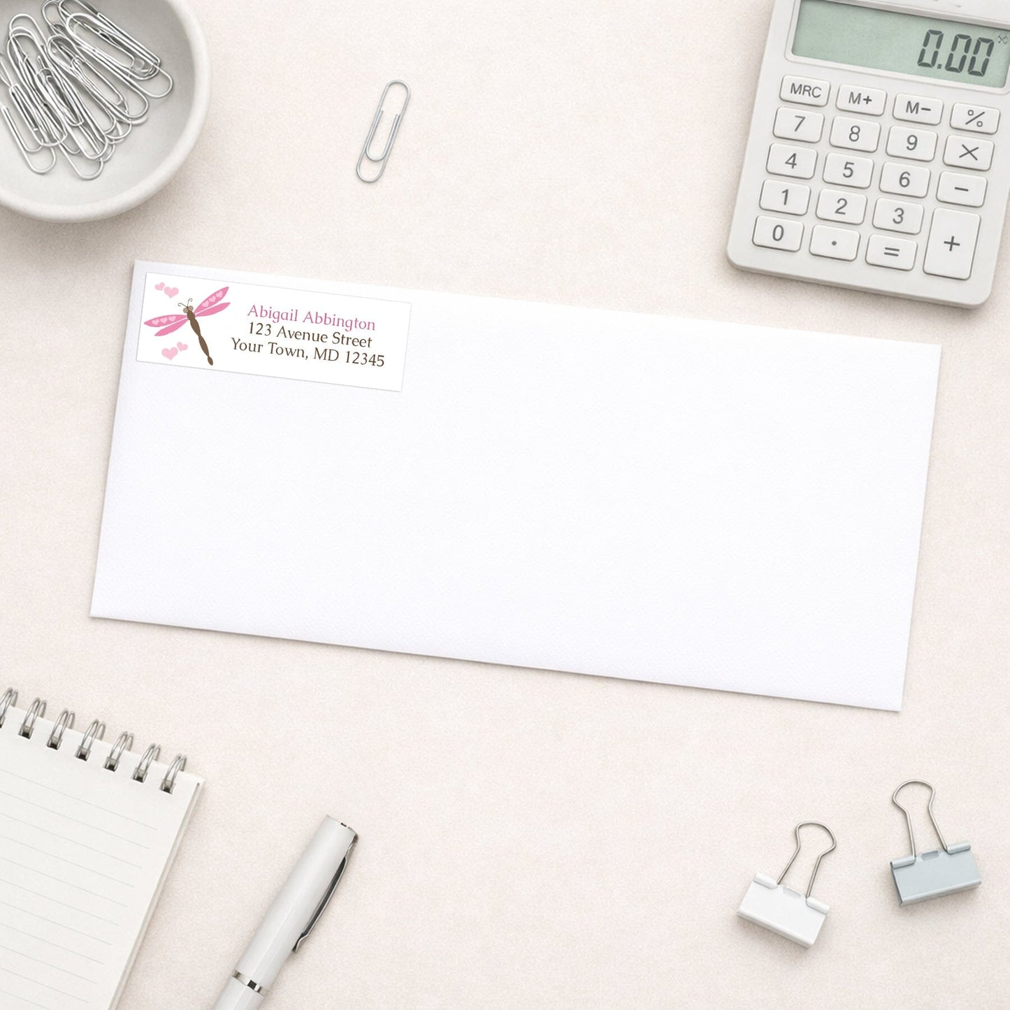 Pink Dragonfly Address Label shown on a white envelope on a desk with office supplies.