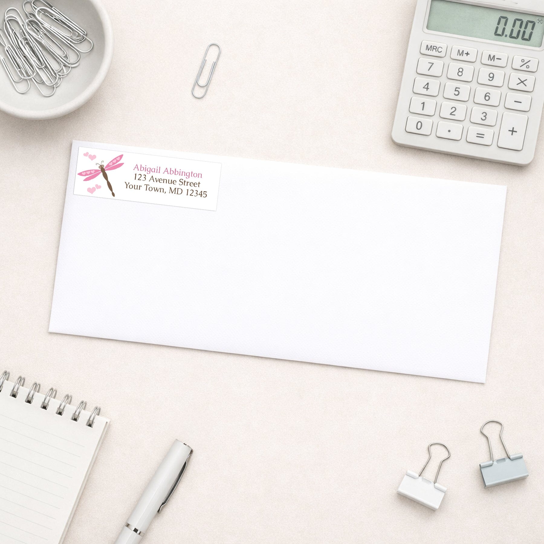 Pink Dragonfly Address Label shown on a white envelope on a desk with office supplies.