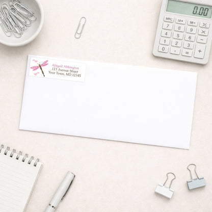 Pink Dragonfly Address Label shown on a white envelope on a desk with office supplies.