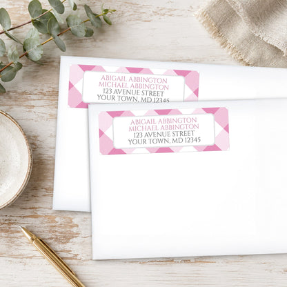 Pink Gingham Address Labels shown on white envelopes on a wooden surface with eucalyptus leaves and a pen.
