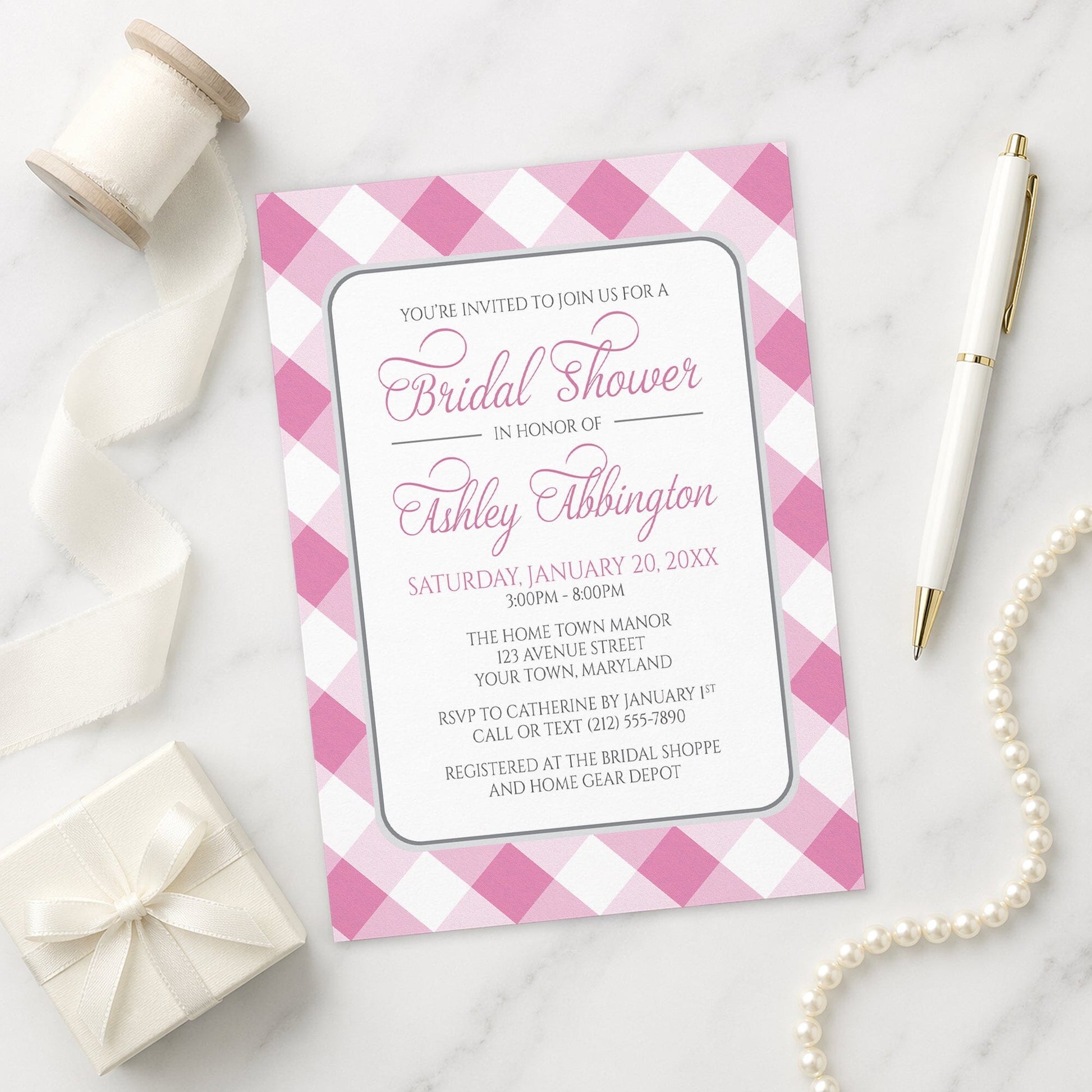 Pink Gingham Bridal Shower Invitation shown on a marble surface with a white gift box, pen, ribbon, and pearls.