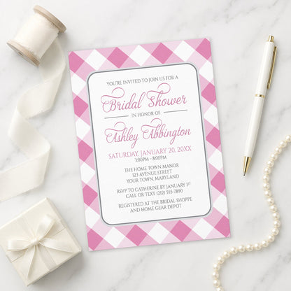 Pink Gingham Bridal Shower Invitation shown on a marble surface with a white gift box, pen, ribbon, and pearls.