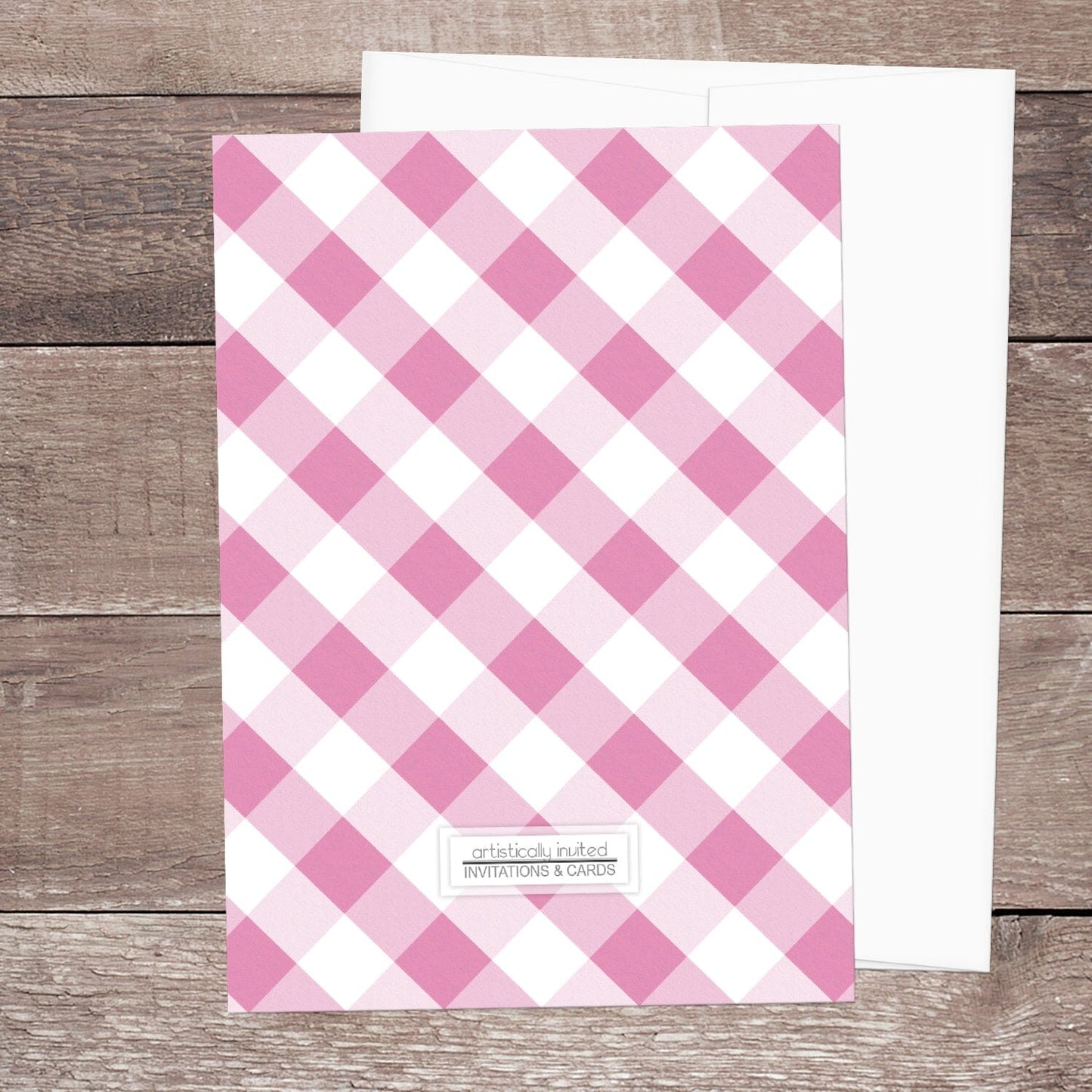 The backside of the Pink Gingham Bridal Shower Invitation shown on a wooden surface with a white envelope.