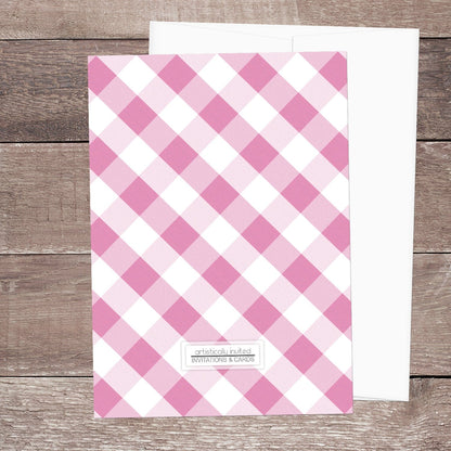 The backside of the Pink Gingham Bridal Shower Invitation shown on a wooden surface with a white envelope.