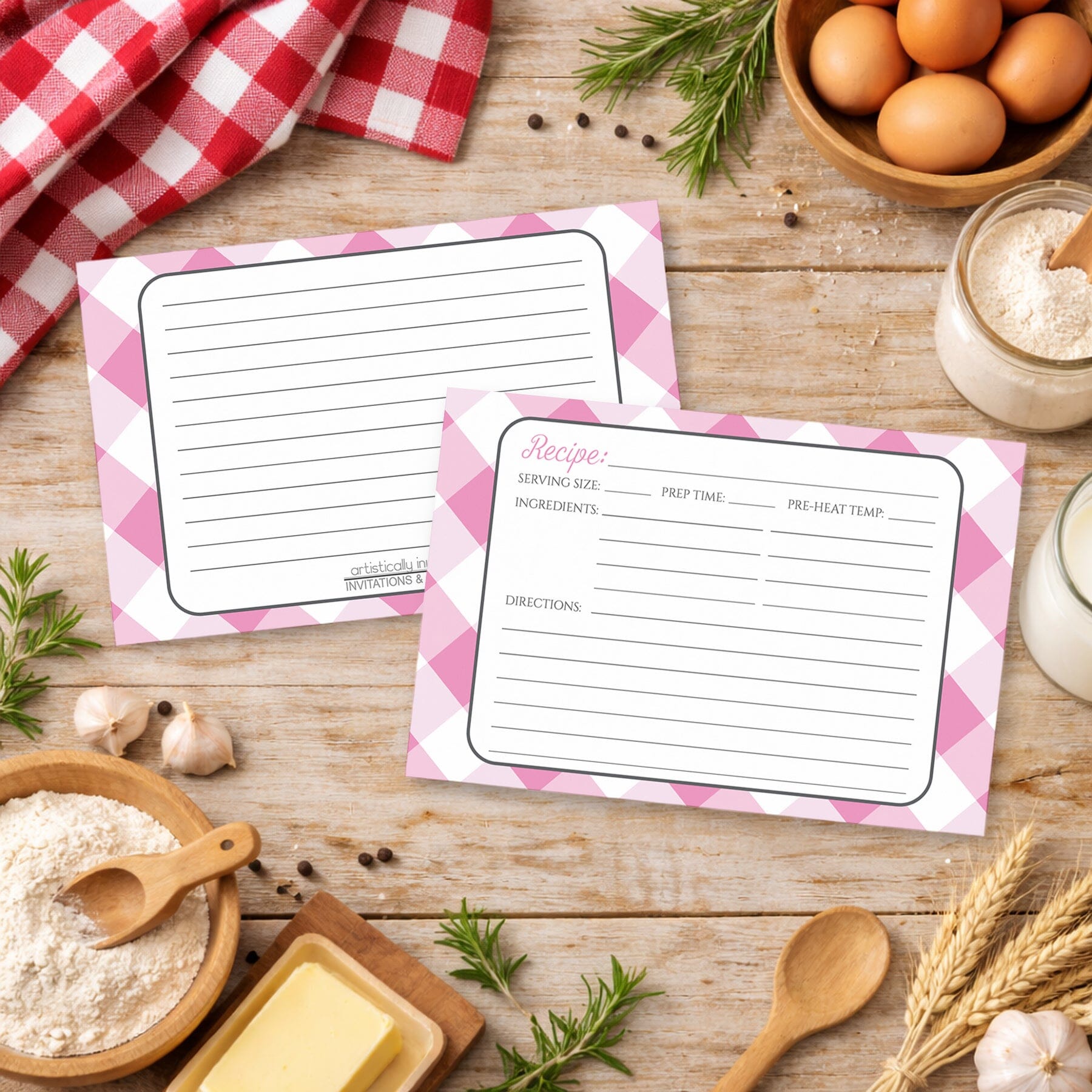Two Pink Gingham Recipe Cards on a rustic wooden surface with country kitchen items around
