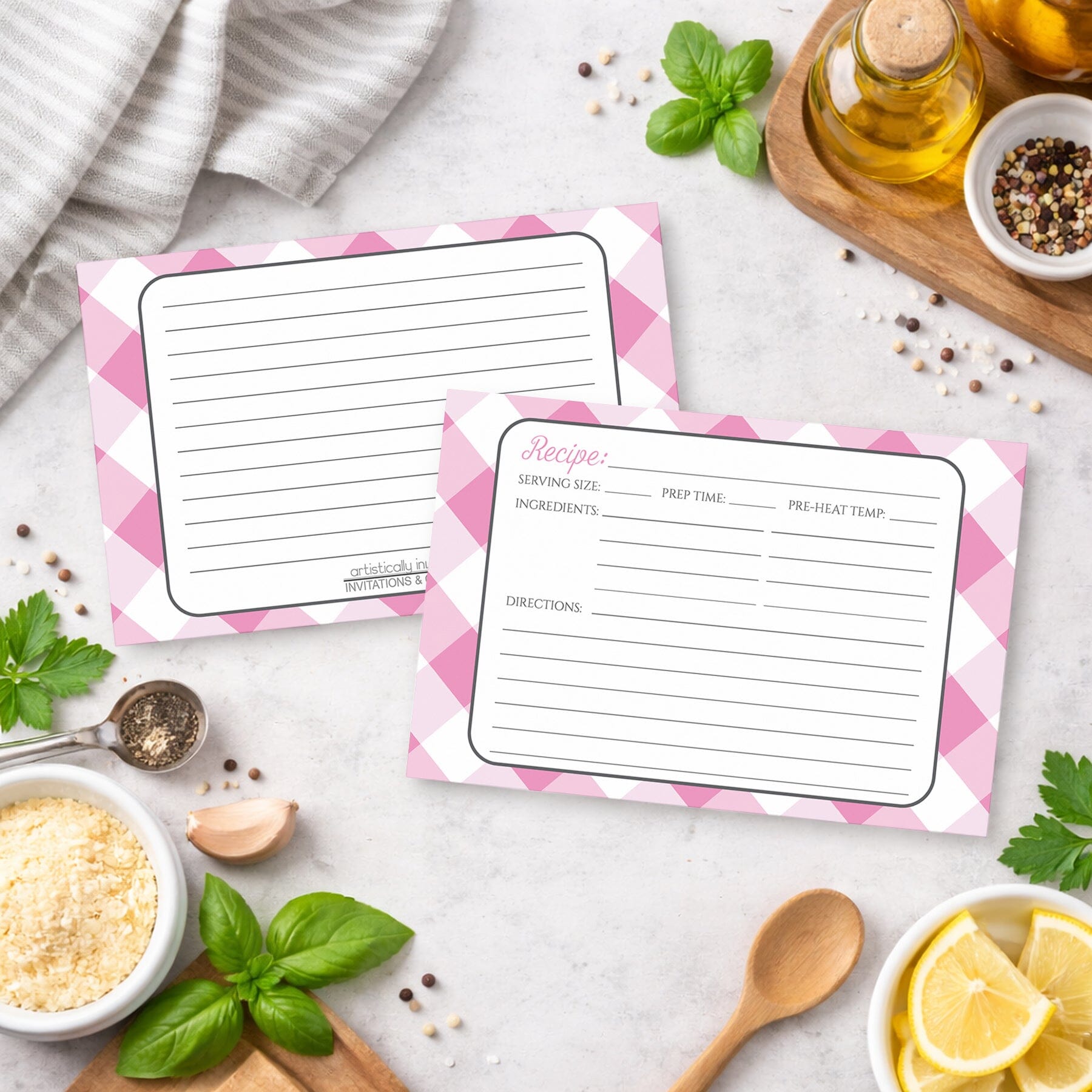 Two Pink Gingham Recipe Cards with pink checkered borders on a kitchen counter with ingredients.
