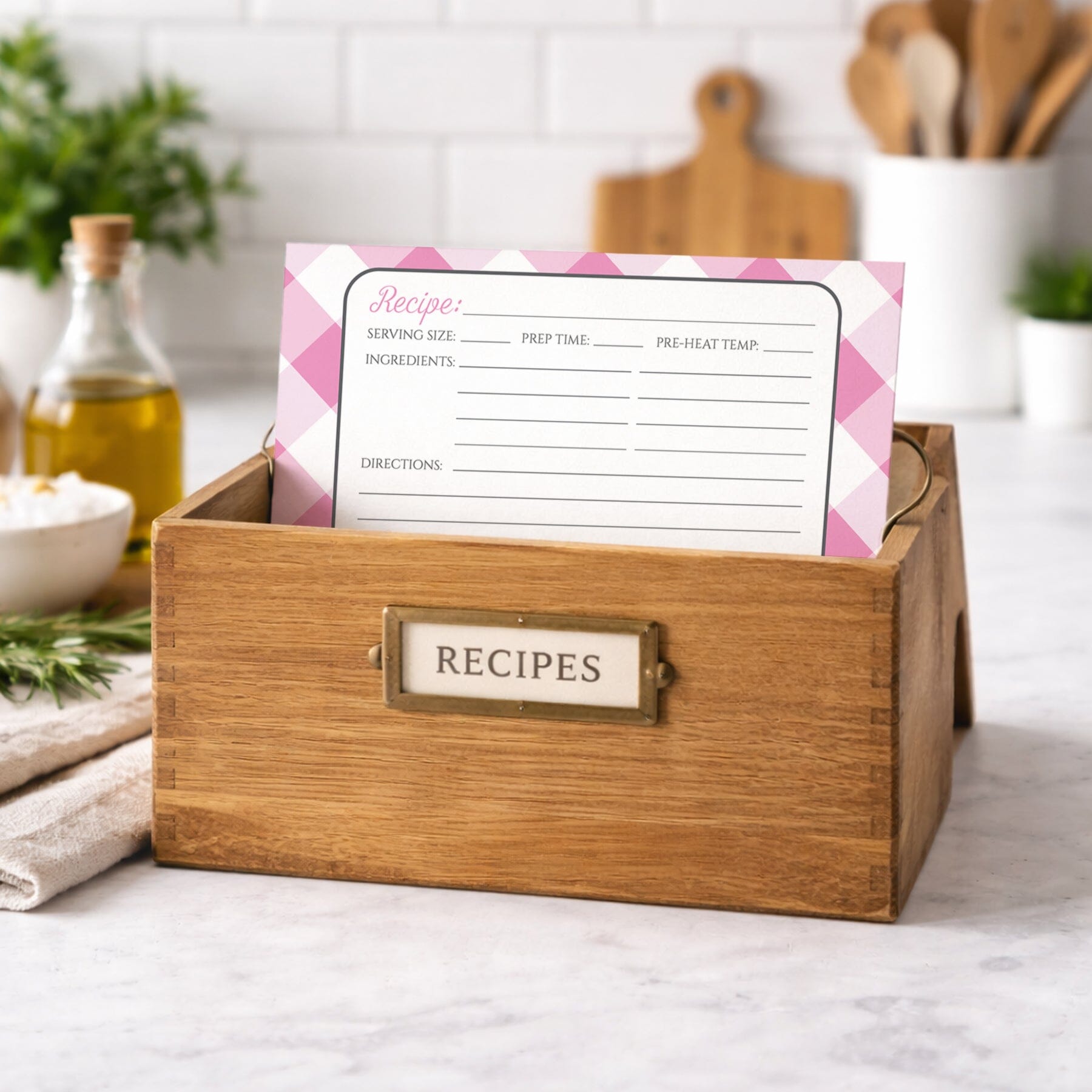 Wooden recipe box with a Pink Gingham Recipe Card on a kitchen counter.