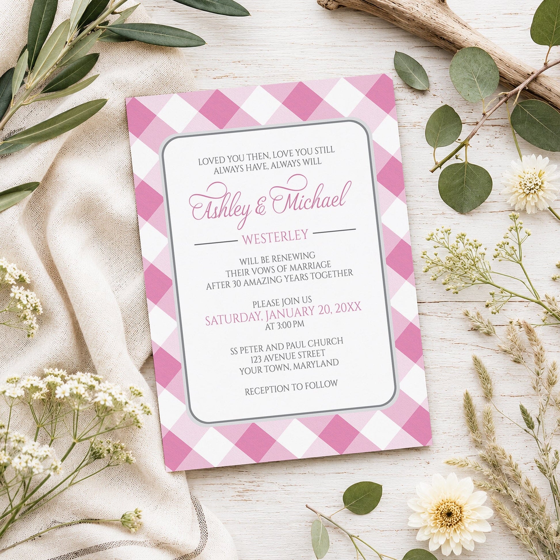 Pink Gingham Vow Renewal Invitation shown on a light wooden surface with spring and summer plants.