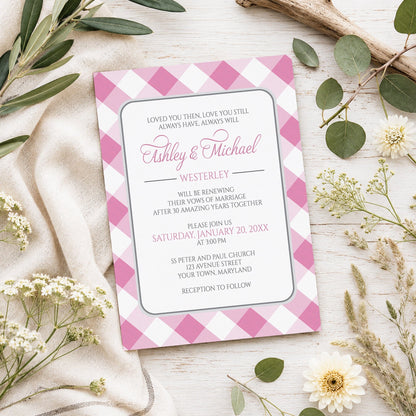 Pink Gingham Vow Renewal Invitation shown on a light wooden surface with spring and summer plants.