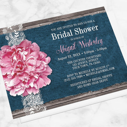 Pink Peony Denim and Lace Rustic Bridal Shower Invitation shown at an angle on a marble surface with a white envelope.
