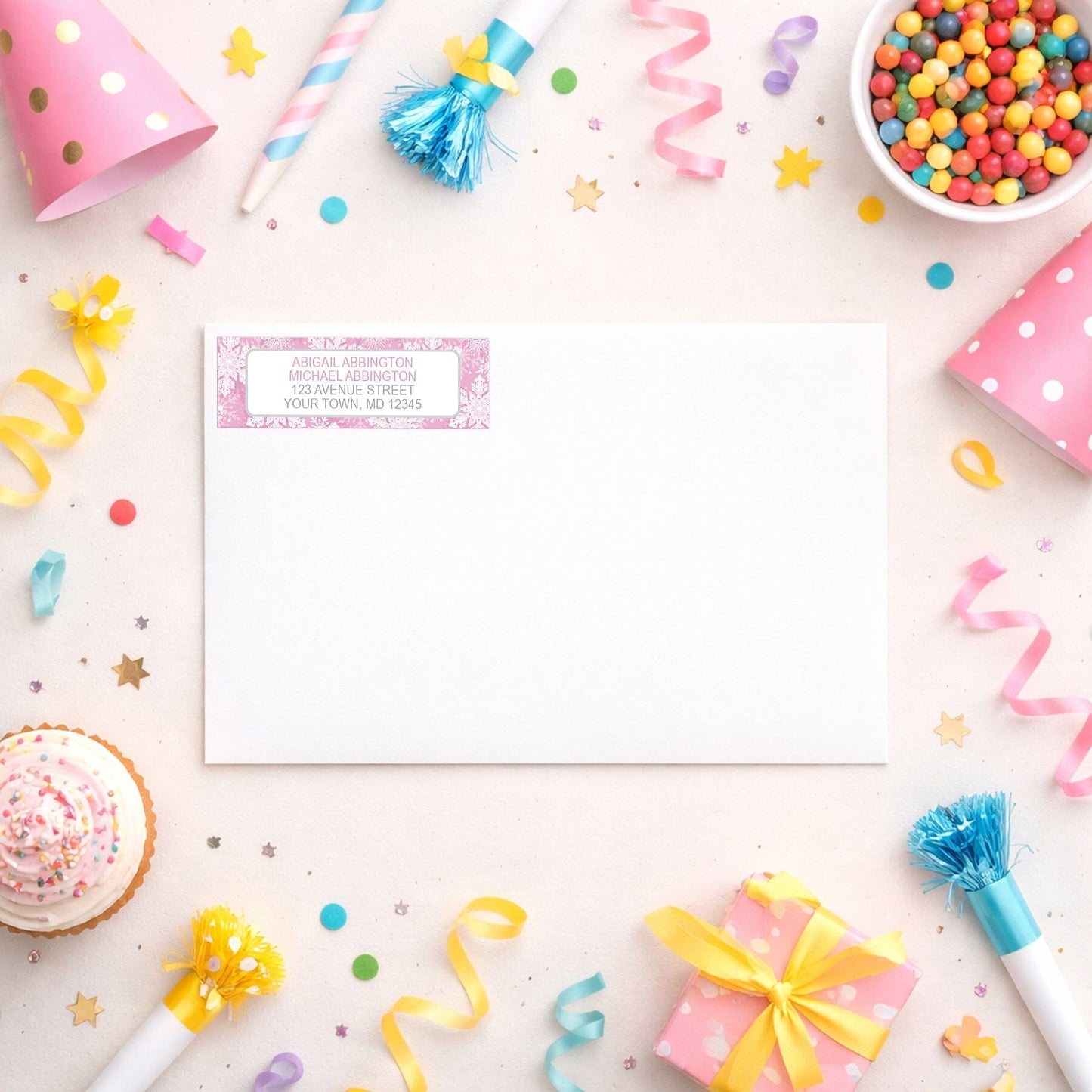 Pink Snowflake Winter Return Address Label shown on a white envelope with party supplies