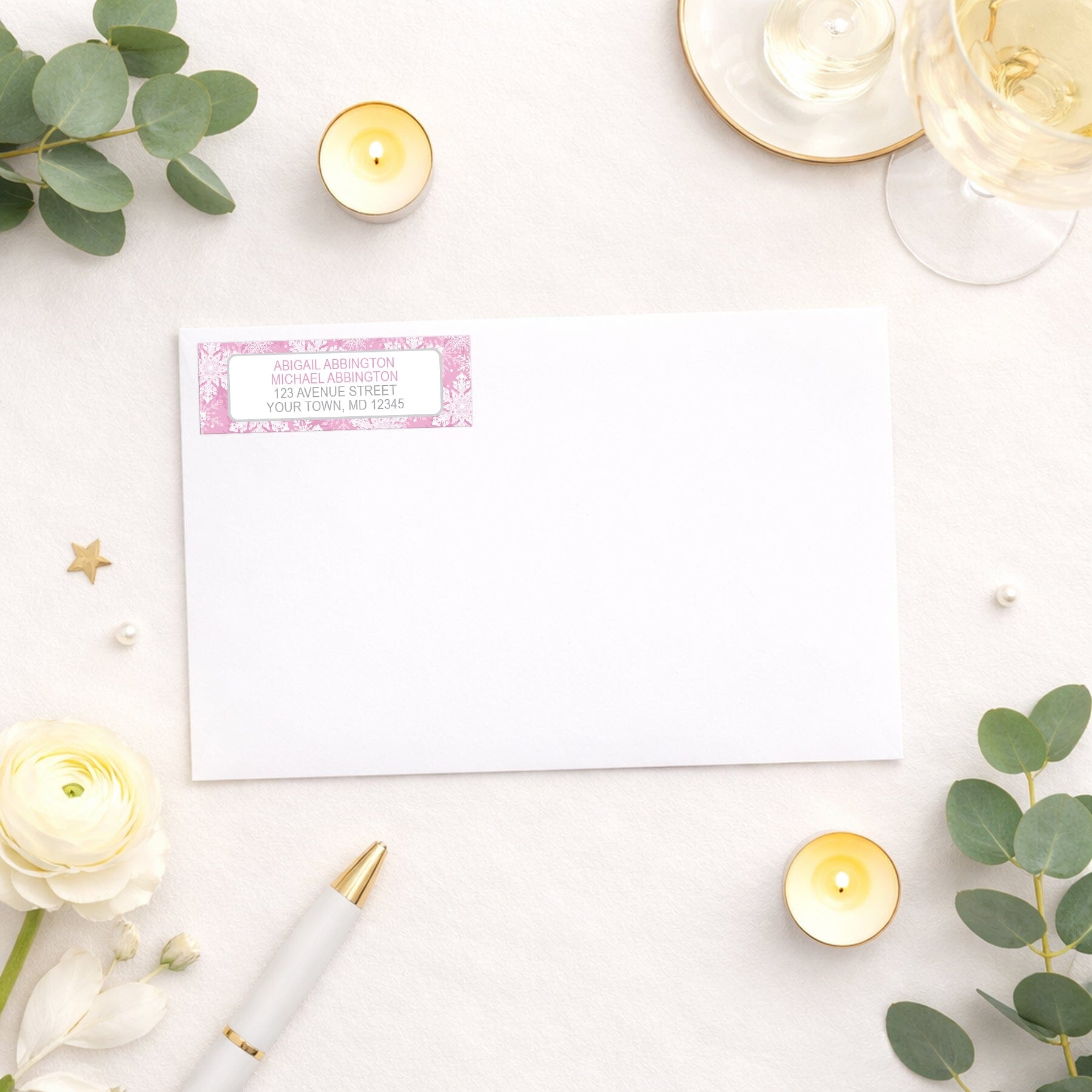 Pink Snowflake Winter Return Address Label shown on a white envelope with wedding and shower supplies