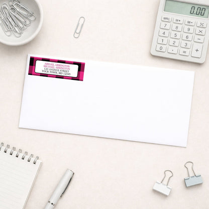 Pink and Black Buffalo Plaid Address Label shown on a white envelope with everyday office supplies