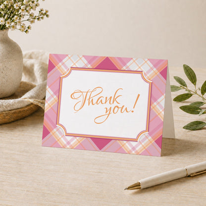 Pink and Orange Plaid Thank You Card shown on a desk with a vase, plants, and a pen.