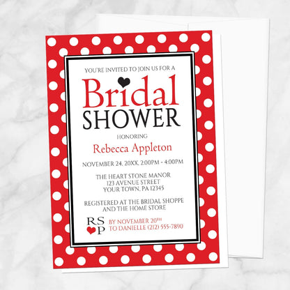 Polka Dot Red Black and White Bridal Shower Invitation shown on a marble surface with a white envelope.