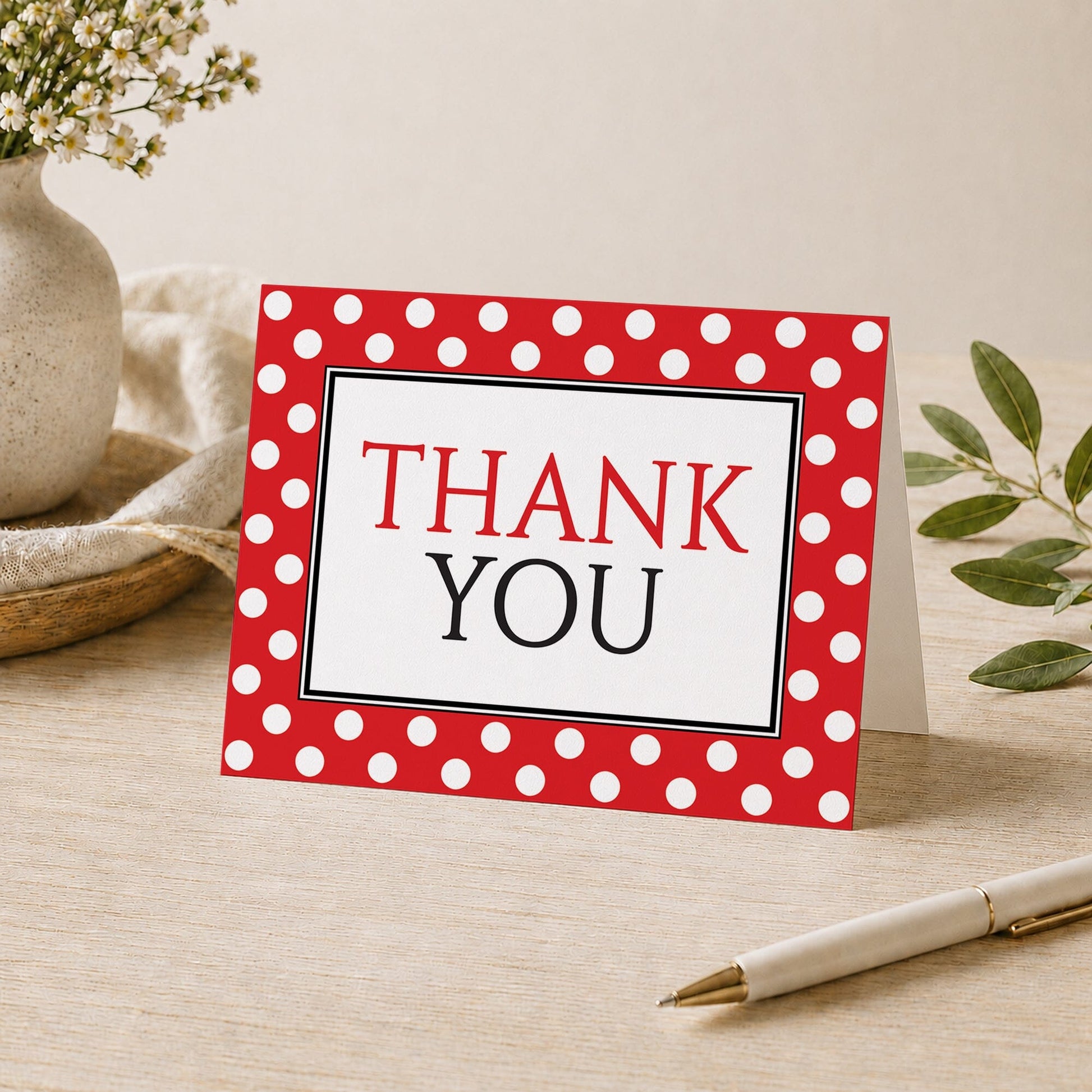 Polka Dot Red Black and White Thank You Card shown on a desk with a vase, plants, and a pen.