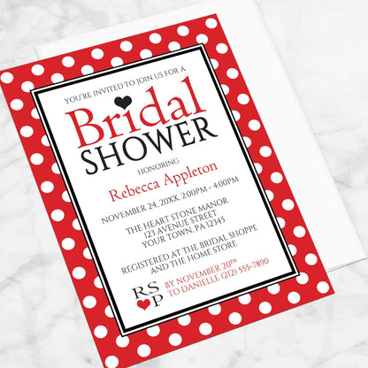 Polka Dot Red Black and White Bridal Shower Invitation shown at an angle on a marble surface with a white envelope.