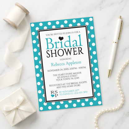 Polka Dot Turquoise Black and White Bridal Shower Invitation on a marble surface with a white gift box, pen, ribbon, and pearls.