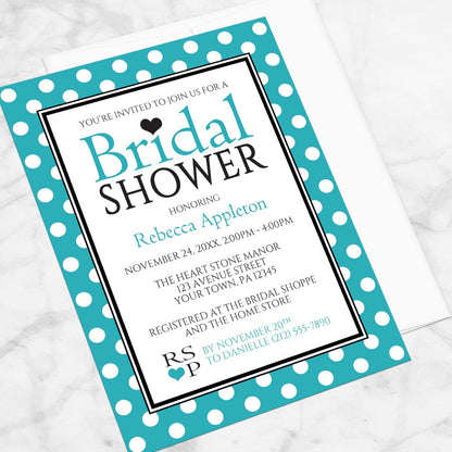 Polka Dot Turquoise Black and White Bridal Shower Invitation shown at an angle on a marble surface with a white envelope.
