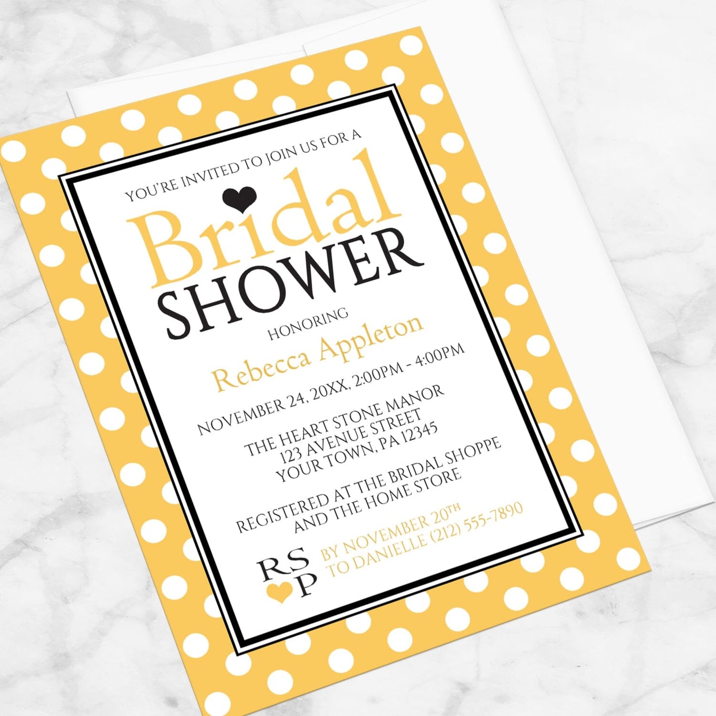 Polka Dot Yellow Black and White Bridal Shower Invitation shown at an angle on a marble surface with a white envelope.
