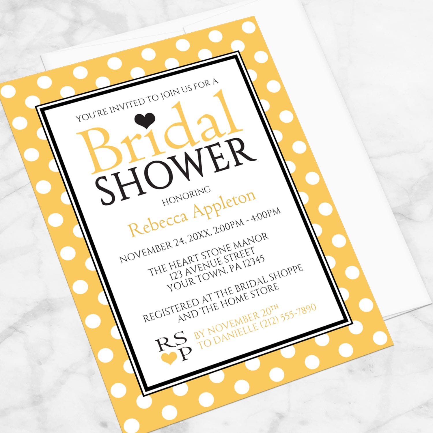 Polka Dot Yellow Black and White Bridal Shower Invitation shown at an angle on a marble surface with a white envelope.