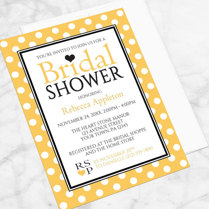 Polka Dot Yellow Black and White Bridal Shower Invitation shown at an angle on a marble surface with a white envelope.