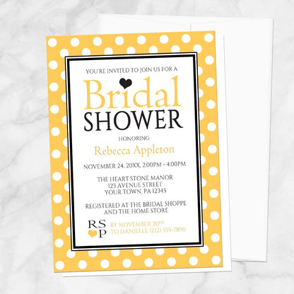 Polka Dot Yellow Black and White Bridal Shower Invitation shown on a marble surface with a white envelope.