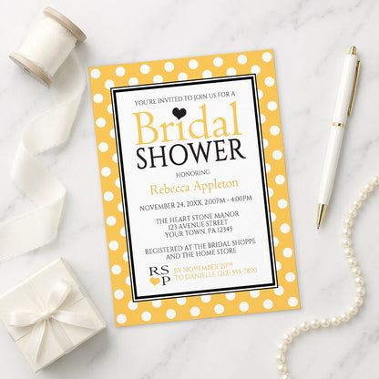 Polka Dot Yellow Black and White Bridal Shower Invitation shown on a marble surface with a white gift box, pen, ribbon, and pearls.