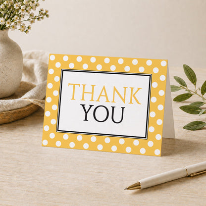 Polka Dot Yellow Black and White Thank You Card shown on a desk with a vase, plants, and a pen.