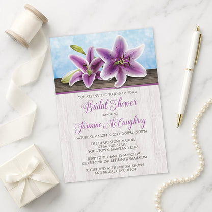 Pretty Floral Wood Purple Lily Bridal Shower Invitation on a marble surface with a pen and gift box.