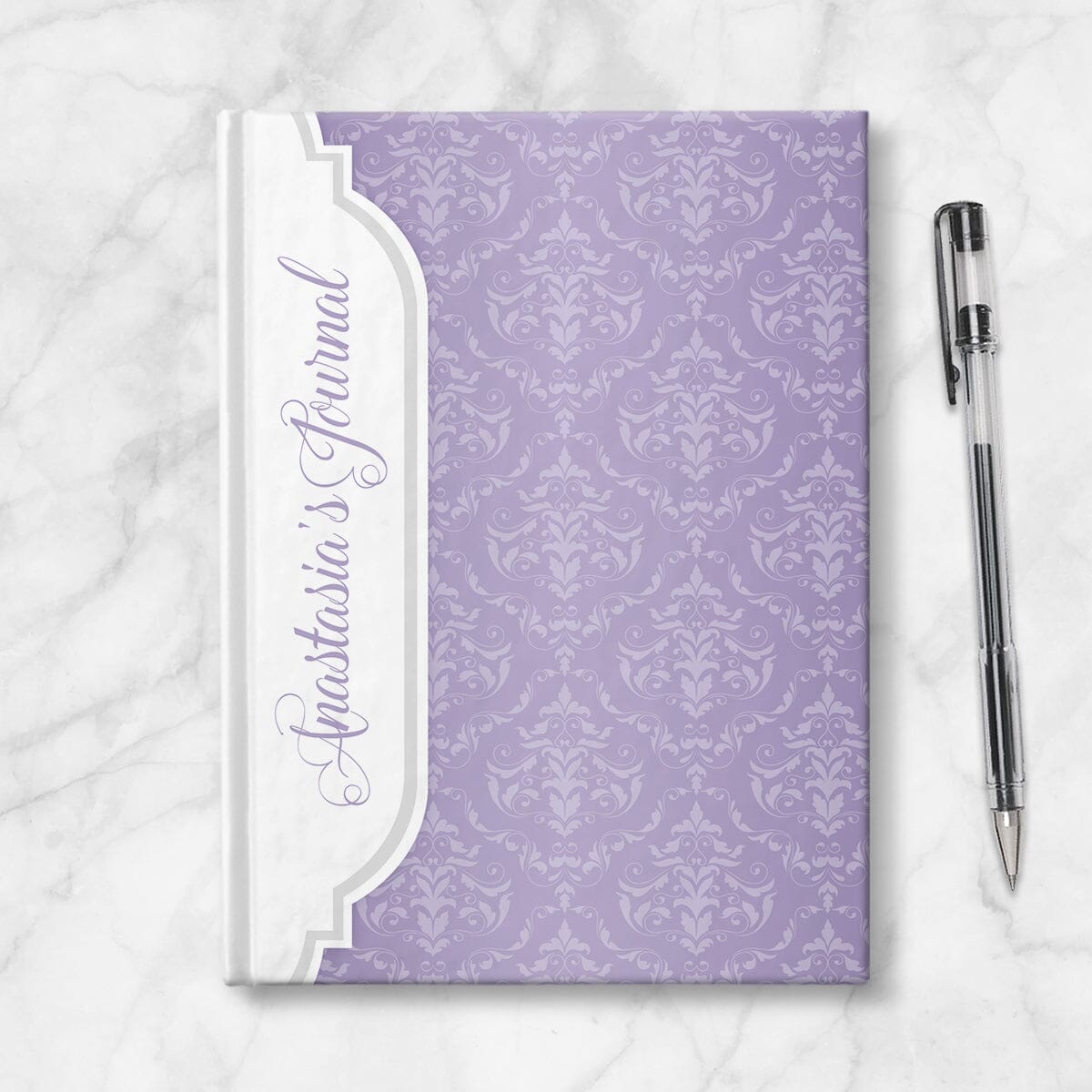 Personalized Purple Damask Journal at Artistically Invited. Image shows the book on a countertop next to a pen.