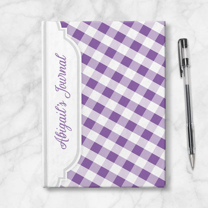 Personalized Purple Gingham Journal at Artistically Invited. Image shows the book on a countertop next to a pen.