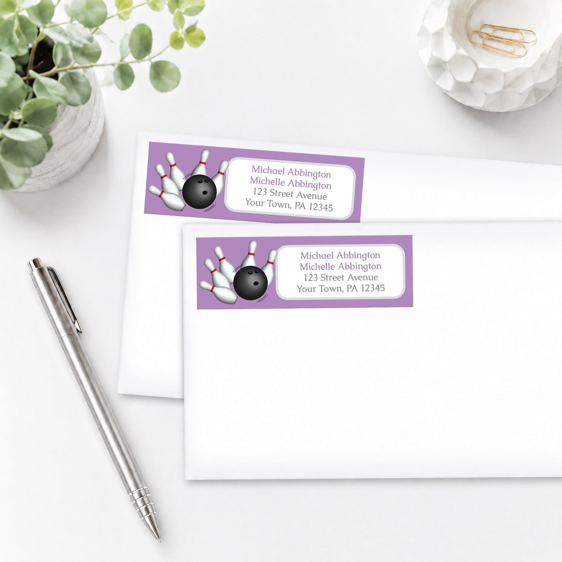 Purple Bowling Address Labels on white envelopes, shown on a white surface with a plant and a pen.