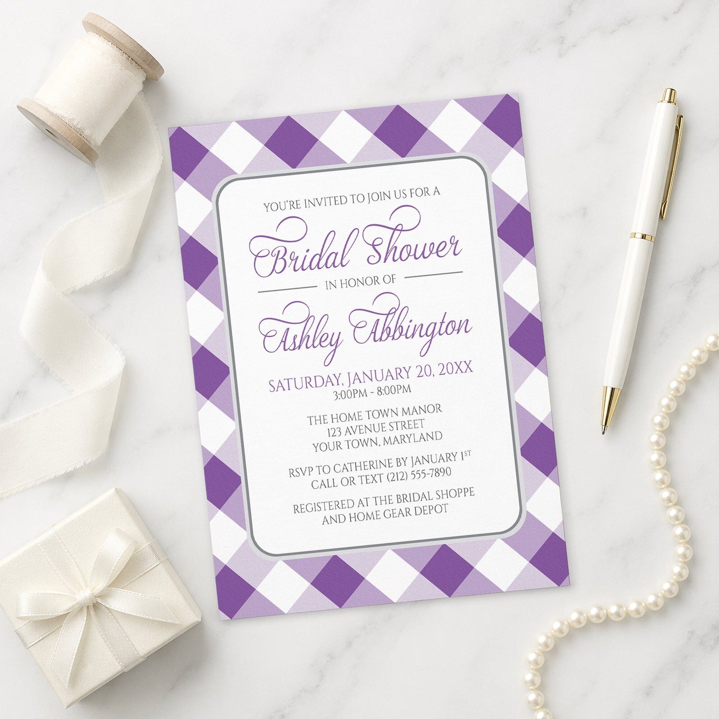 Purple Gingham Bridal Shower Invitation on a marble surface with a gift box, pen, and pearls.