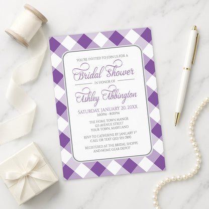 Purple Gingham Bridal Shower Invitation on a marble surface with a gift box, pen, and pearls.