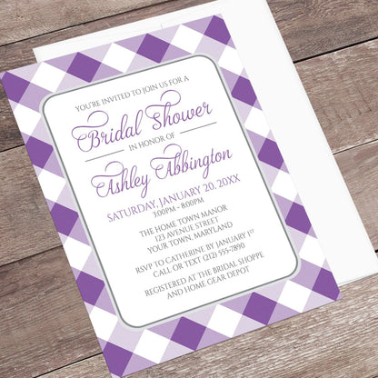 Bridal shower invitation with purple and white gingham check border, displayed at an angle with a white envelope on a wooden surface