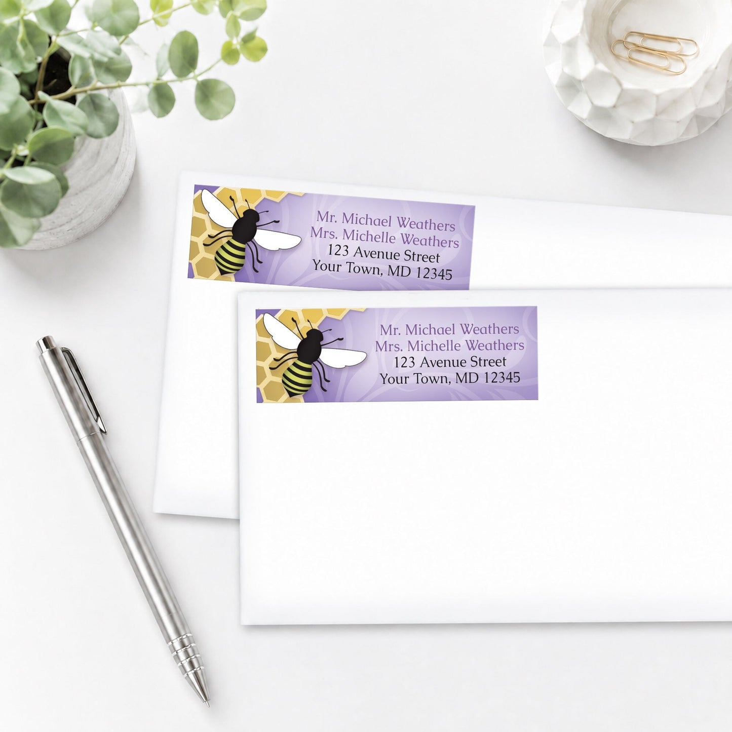 Purple Honeycomb Bee Address Labels shown on white envelopes, on a white surface with a plant and a pen.