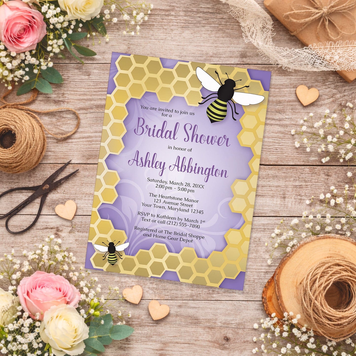 Purple Honeycomb Bee Bridal Shower Invitation on a wooden surface with flowers and twine.