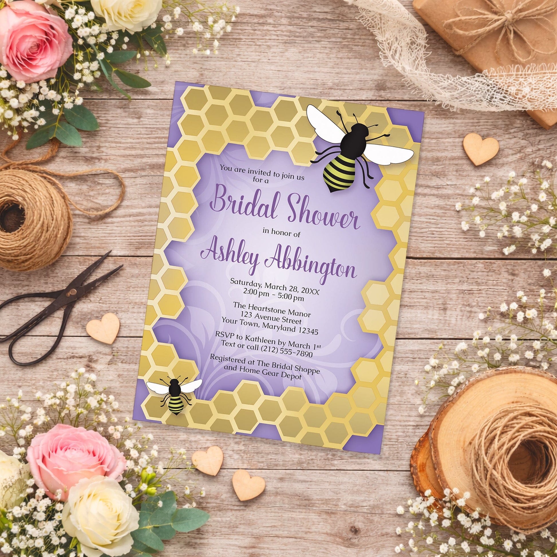 Purple Honeycomb Bee Bridal Shower Invitation on a wooden surface with flowers and twine.
