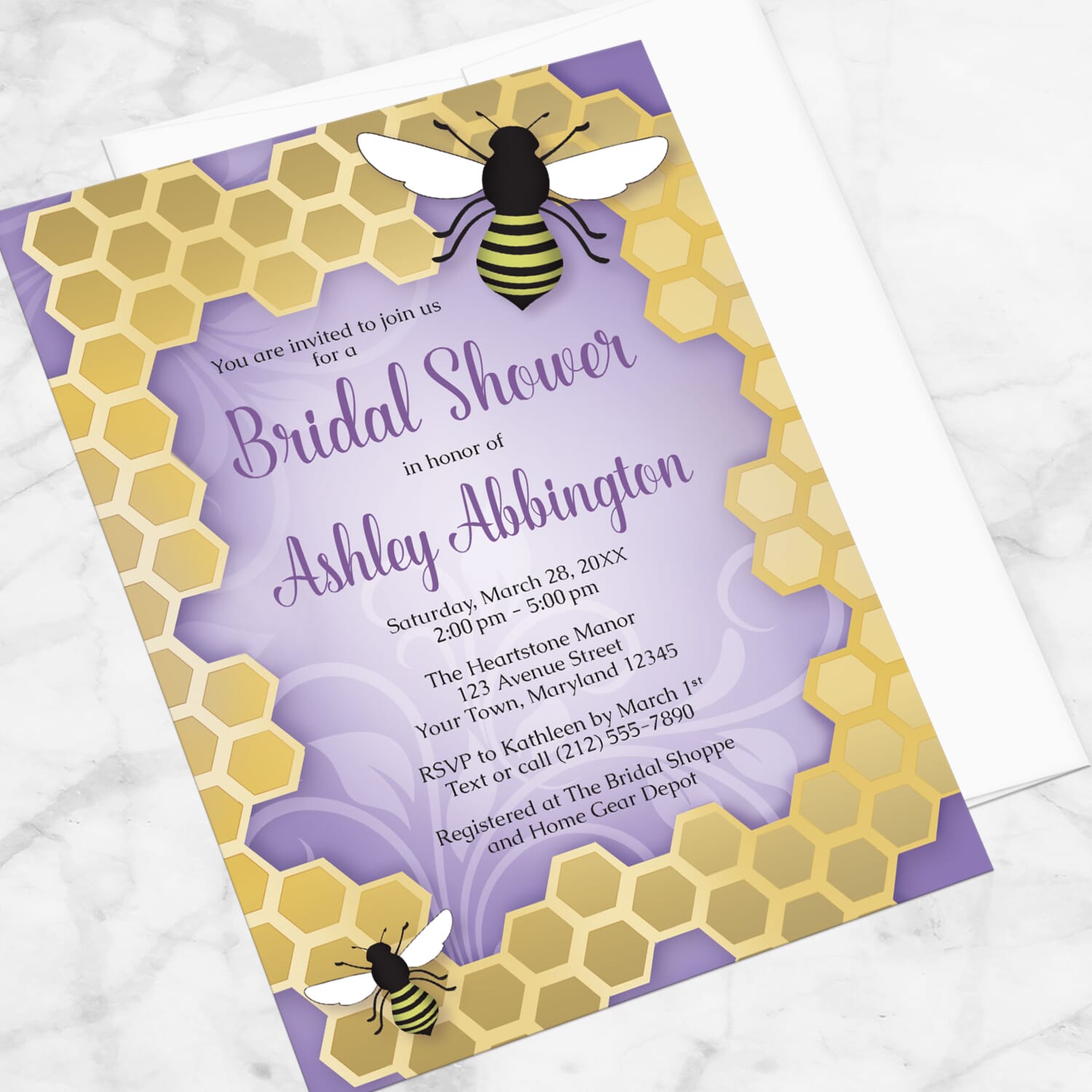 Bee bridal shower invitation with 2 bees on a honeycomb frame over a purple background, displayed at an angle with a white envelope on a marble surface